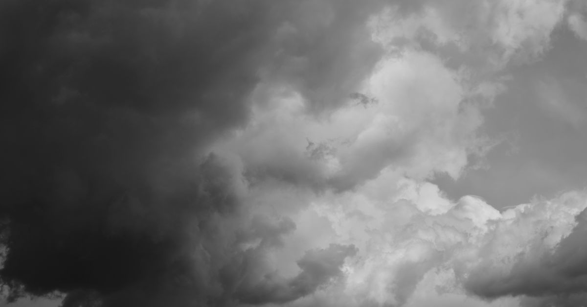 A moody black and white photograph capturing stormy clouds in the sky.